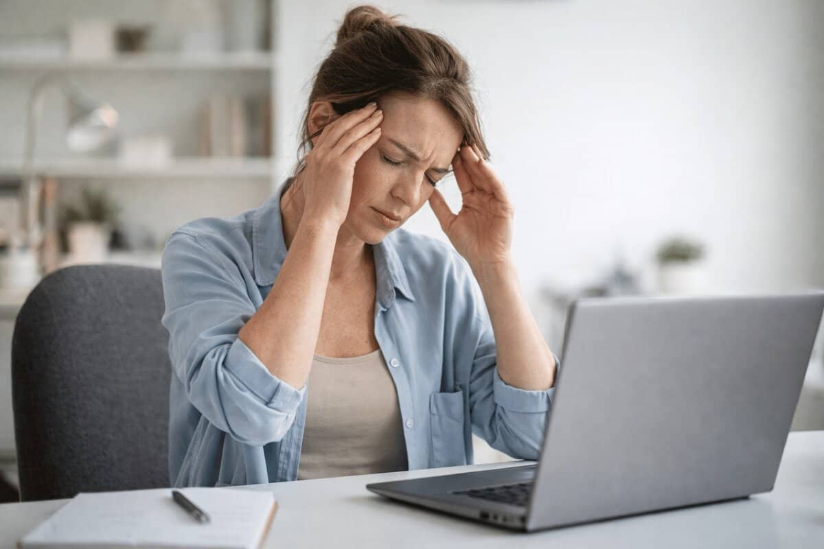 persona con cefalea tensional y tensión cervical trabajando con ordenador